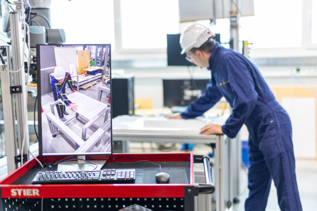 A worker is shown at his working station while a system analyses his posture